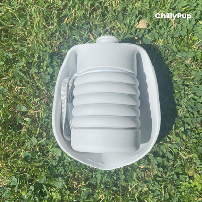 One foldable silicone water bottle completely folded up on grass.